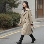 여자가 미디 길이 베이지색 트렌치코트를 입고 거리를 걷는 스타일링 사진