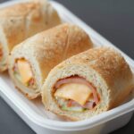 햄과 치즈가 돌돌 말린 롤샌드위치가 예쁘게 썰어져 도시락에 담겨 있음