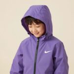 나이키 키즈 바람막이 실용성과 스타일 완벽한 선택 라벤더 컬러의 나이키 키즈 스우시 윈드러너 바람막이를 입은 아이가 밝은 배경에서 웃고 있음