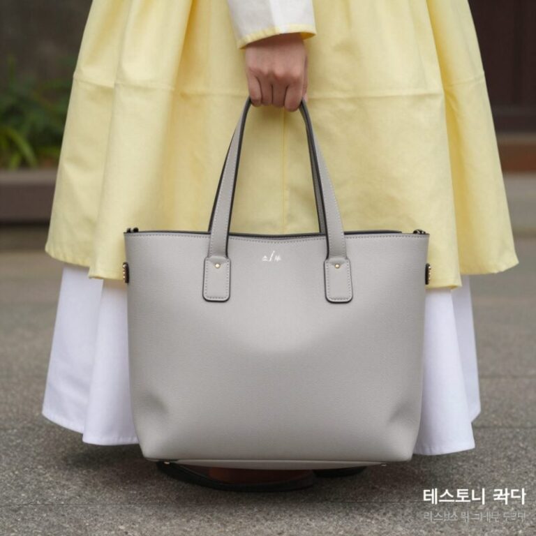 테스토니 위저드 34 애쉬 그레이 가죽 토트백이 바닥에 놓여 있고, 연한 라임색 바람막이와 화이트 미니스커트와 함께 코디된 모습