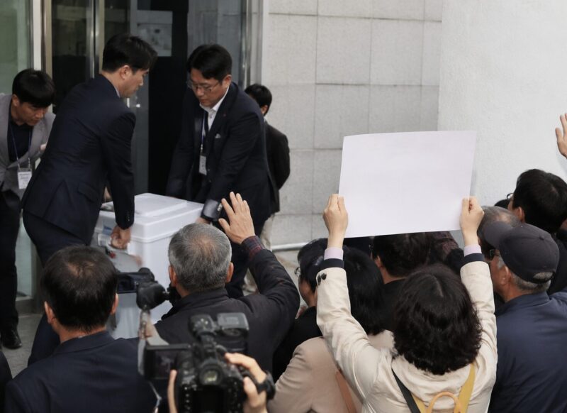 서울 송파구 잠실7동 투표소 앞에서 투표함 반출을 막는 시민들의 모습과 '재선거'를 요구하는 손팻말