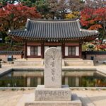 용인 와우정사 단풍 명소 실내 관람 용인 와우정사 입구 불두상과 연못, 뒤로 단풍나무가 보이는 풍경