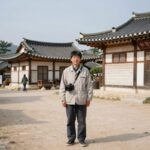 타임슬립 천일야사 역사 체험의 새로운 세계 타임슬립 천일야사 시간 여행자가 조선 시대 전통 마을을 배경으로 서 있는 모습