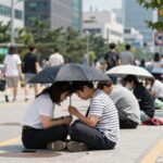 사상 첫 폭염중대경보 발령 기준과 대응법 폭염중대경보 발령 시 야외 활동을 중단하고 그늘에서 휴식하는 사람들의 모습