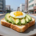 올리브오일로 구운 슬랩 브레드 토스트 위에 아보카도와 삶은 계란 샐러드를 토핑한 오픈 샌드위치